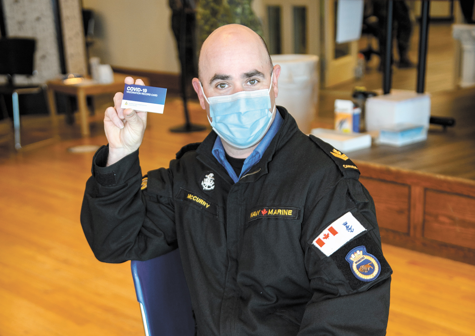 Master Sailor Jamie McCurry holds up his military vaccine card after receiving his shot. Photo by Sailor First Class Mike Goluboff, Imagery Technician