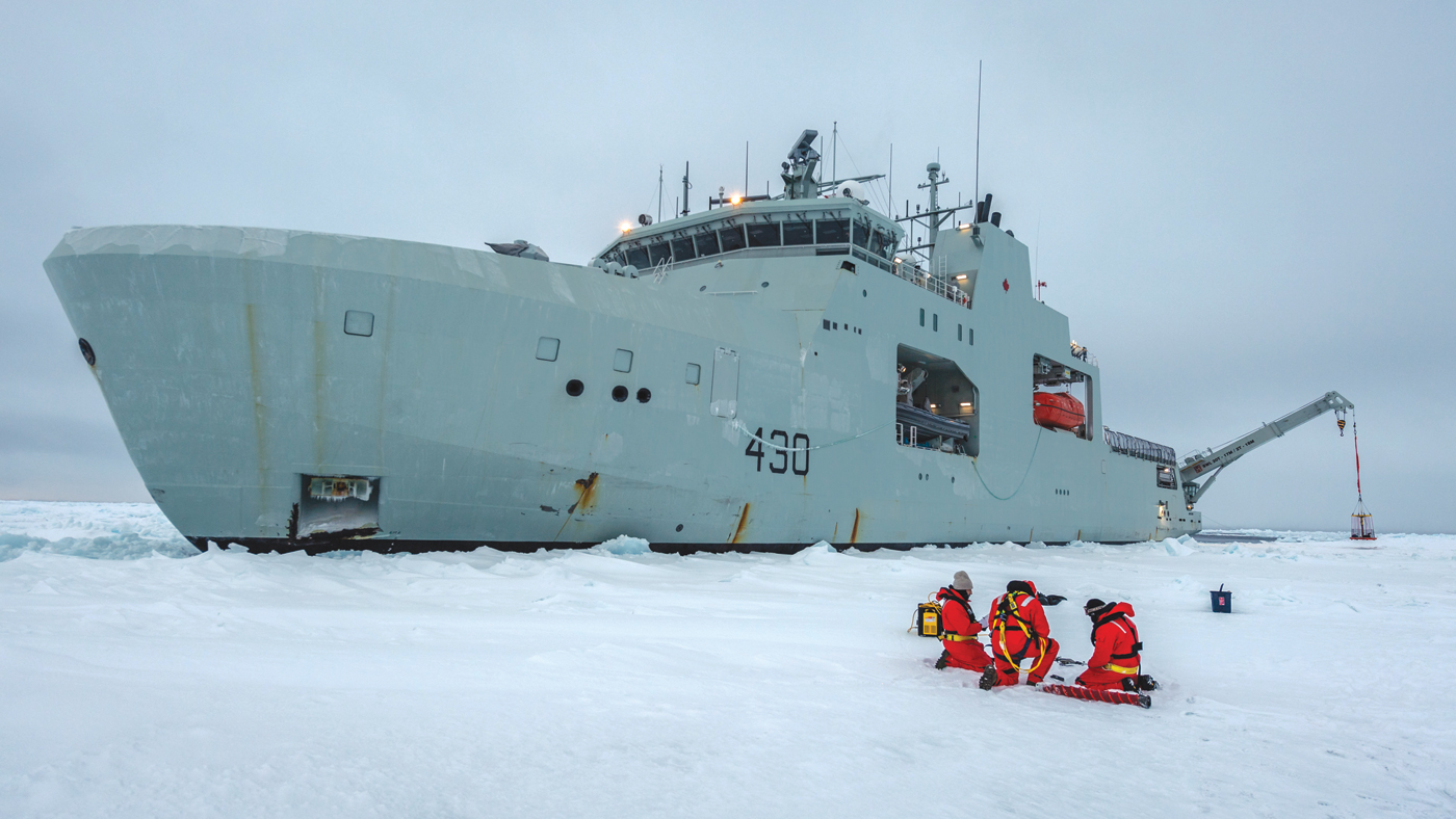 Civlian contractors and crew members conduct ice operations alongside HMCS Harry Dewolf during Cold Weather Trials near Frobisher Bay on Feb 20. Photo by Corporal David Veldman, Canadian Armed Forces Photo