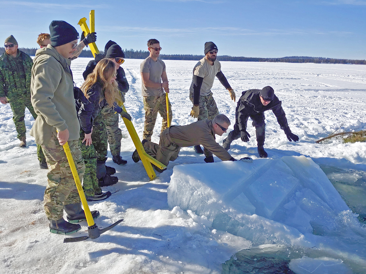 Participants cut a hole in the ice at Sheridan Lake before setting up their shelters at ICEDIVEX23 a five-day training  exercise led by Fleet Diving Unit (Pacific). An international team of 39 divers arrived at the lake to challenge their extreme cold-weather diving skills. 