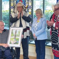 Rolland Bremner, résident métis du Veterans Memorial Lodge, reçoit en cadeau une peinture commandée à l'artiste Andrew Bartley de Port Alberni, en compagnie d'Eric Palkey (coordinateur de l'engagement communautaire du WSÁNEĆ Leadership Council et chef héréditaire de la Première nation Tsawout), de Janet Power (directrice du Veterans Memorial Lodge) et de Calvin Hunt (maître sculpteur). Calvin Hunt (maître sculpteur, artiste du mât totémique Kwakwaka'wakw de la côte nord-ouest).