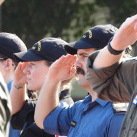 Petty Officer Second Class Kyle Medwid and Sailor First Class Sarah Sundac, members of HMCS Edmonton, salute while Canada's national anthem plays.