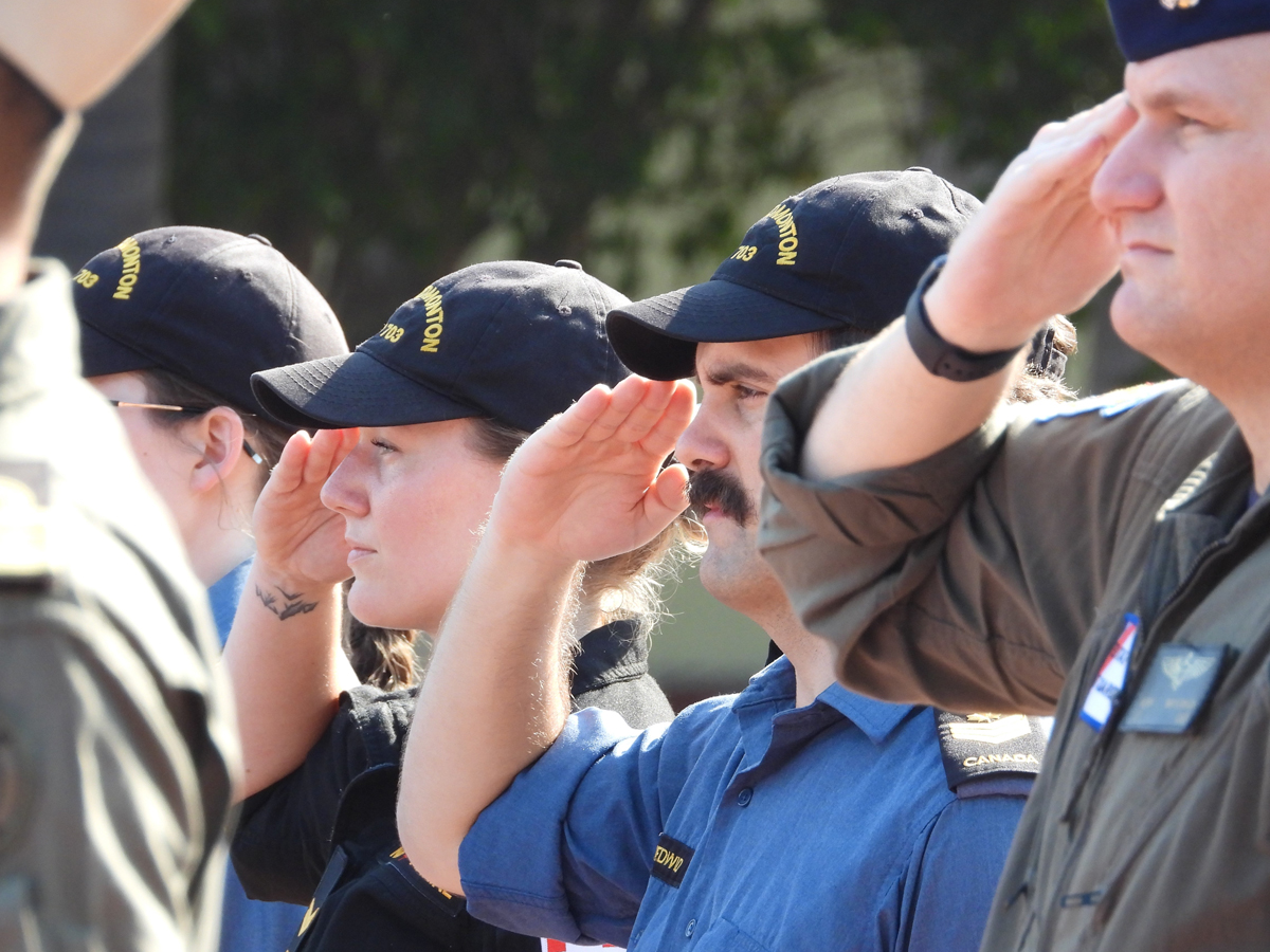 Petty Officer Second Class Kyle Medwid and Sailor First Class Sarah Sundac, members of HMCS Edmonton, salute while Canada's national anthem plays.