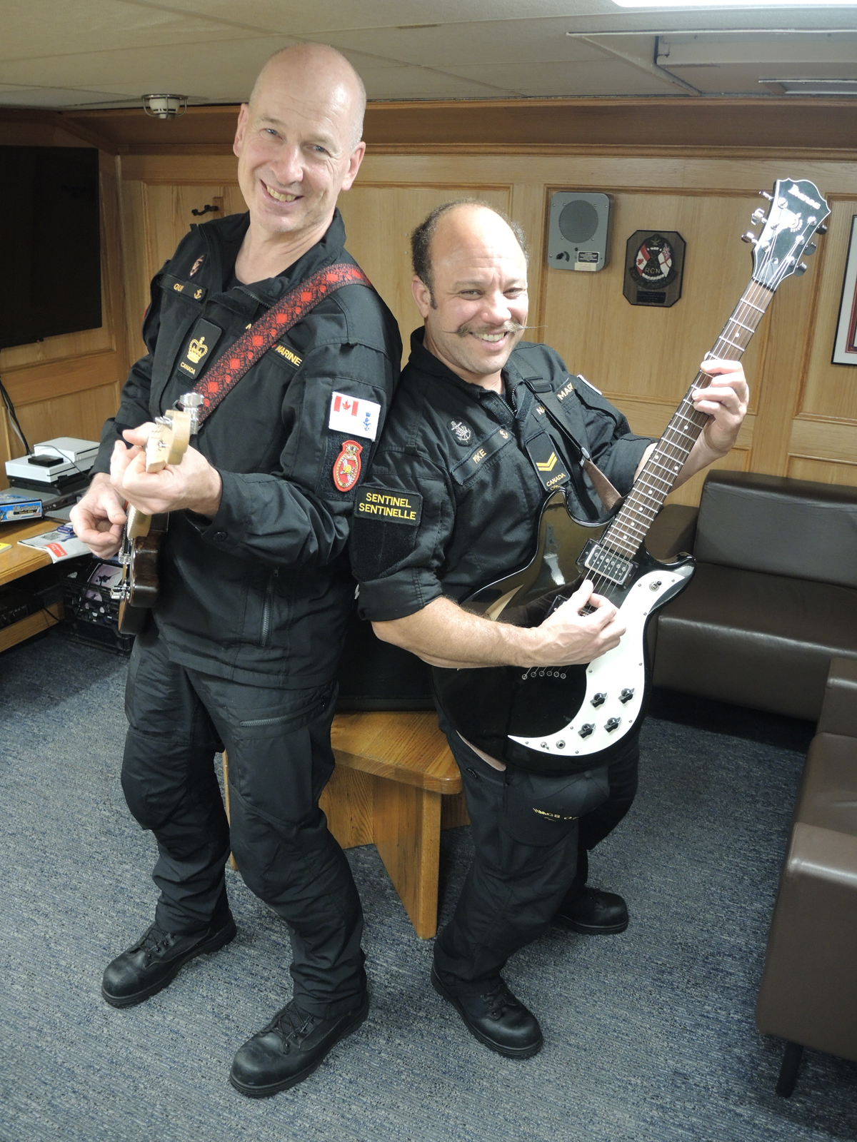 Le Maître de première classe Paul Quin et le Matelot de première classe Syl Pike s'exercent à jouer de la guitare dans le mess des maîtres et des premier maîtres à bord du NCSM Ottawa. Les deux marins ont lancé un programme visant à fournir des instruments de musique aux marins à bord du navire lors de son prochain déploiement dans la région indo-pacifique. Photo : Peter Mallett/Lookout Newspaper : Peter Mallett/Lookout Newspaper.  