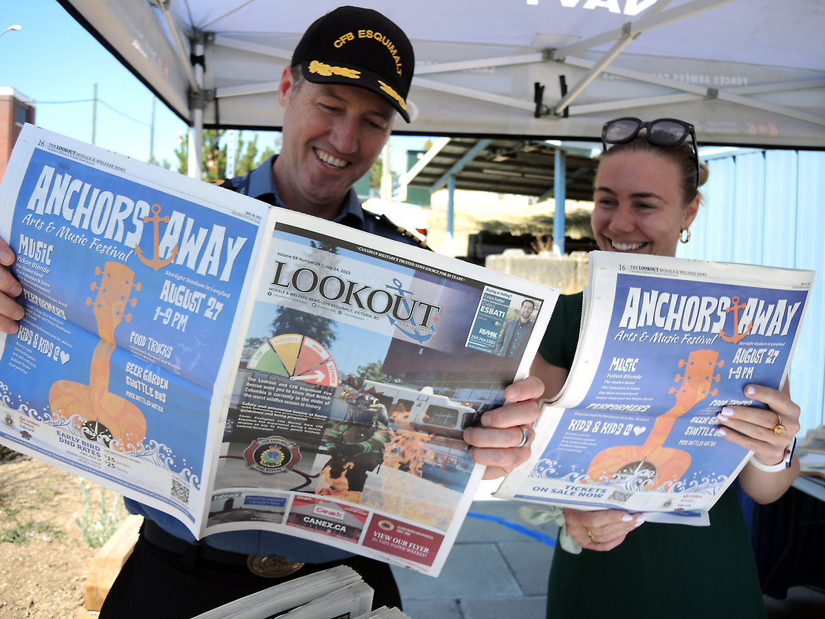 Le Capitaine de vaisseau Kevin Whiteside, commandant de la BFC Esquimalt, lit un exemplaire du journal Lookout avec Jazmin Holdway, gestionnaire de Lookout, lors du salon professionnel industriel Ship to Shore à l’aréna Wurtele, le 1er août.  Photos : Peter Mallett/Lookout Newspaper 