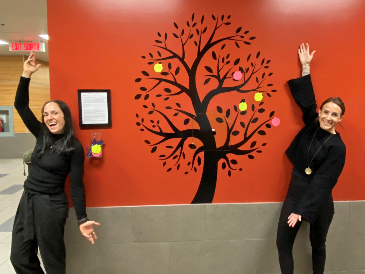 Danielle Yole et Ashley Evans, du groupe de travail sur le bien-être social et mental de la Stratégie de santé et de bien-être des FMAR(P), posent avec l’arbre de la gratitude nouvellement érigé à l’Installation de maintenance de la Flotte (IMF) du Cap-Breton.