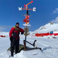 A/SLt Kayvan Aflaki stands with a landmark signpost at Captain Arturo Prat Base, a Chilean Antarctic research station located on Greenwich Island, after completing a replenishment with the crew members of Chilean offshore patrol vessel Marinero Fuentealba. Photo: ST Felipe Olea.