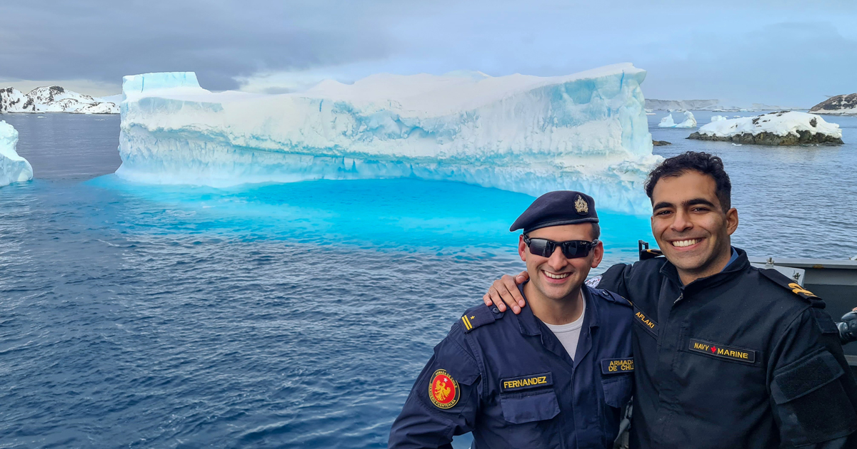 A/SLt Kayvan Aflaki (right) and T2 Francisco Fernandez of the Chilean Navy stand before a glacier as they transit across the Bransfield Strait aboard Marinero Fuentealba en route to complete a replenishment. Photo: ST Felipe Quijarro
