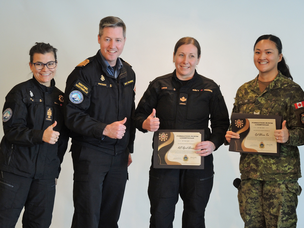 (À gauche) Le Premier maître de première classe Susan Frisby, chef de la base, et le Capitaine de vaisseau Kevin Whiteside, commandant de la base, remettent au Matelot-chef April Davis, de la salle des rapports de la base, et au Caporal Alison Tso, du QG MARPAC/JTF(P), le prix du membre militaire subalterne de la logistique de la formation. Toutes les photos : Peter Mallett, Lookout Newspaper
