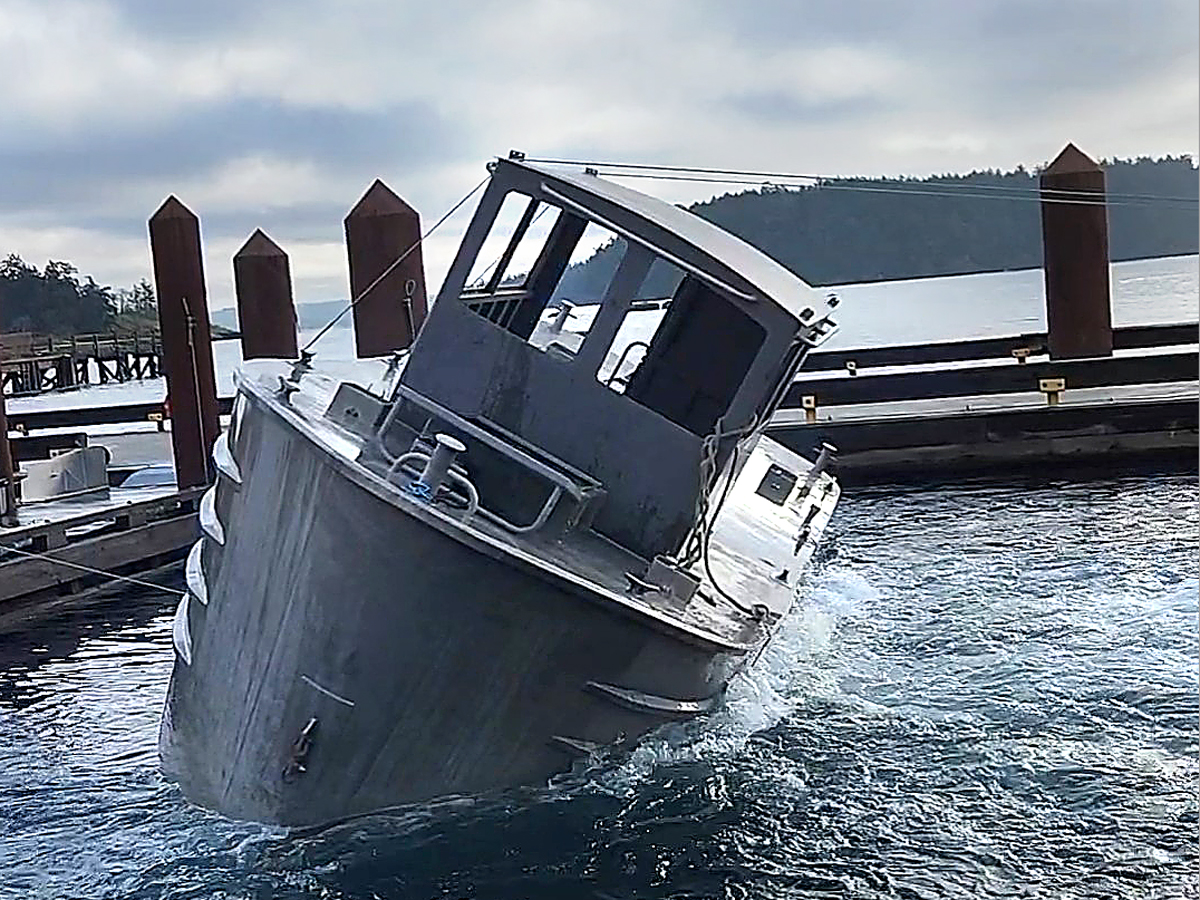 Wheel House, Diver Assisting Direction – RCMP Marine Tactical Operations Instructors participate in a training exercise involving a capsized boat off ‘D’ Jetty at CFB Esquimalt, Jan. 17. The specially-designed training vessel they were using is built with several airtight compartments that allows it to float upside down and adjust the air pocket inside. Photo: RCMP