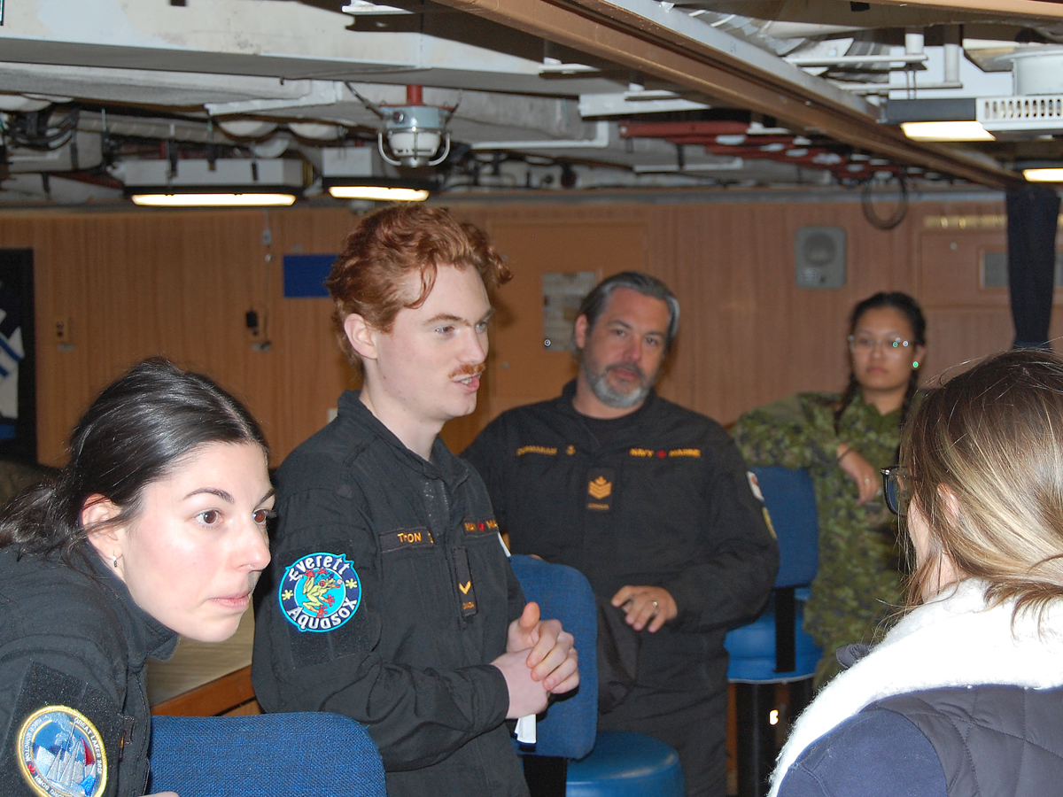 Le matelot de deuxième classe Zachary Thompson (au centre) discute avec des recruteurs de la Réserve navale.
