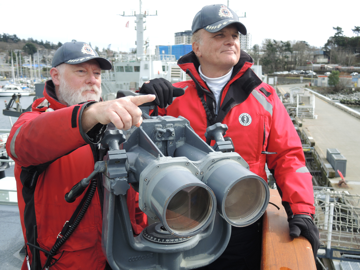 (À gauche) Brian Whittaker, pilote 1 et officier d’amarrage et de formation du capitaine de port de Sa Majesté (CPSM), et Tansel Erkmen, pilote 2 du CPSM, observent les sites d’atterrissage potentiels sur Y-Jetty depuis un pont d’observation à bord du NCSM Saskatoon, le 29 février. Les deux sont des employés civils et des membres de la flotte auxiliaire de la Direction des opérations portuaires et des services d’urgence. Photo : Peter Mallett/Lookout Newspaper.