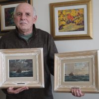 David Emmerson holds his pair of LCdr Riordon paintings numbers 18 and 12 in the Convoy series. It was their purchase in 2020 that got him started on the project of researching their origins.