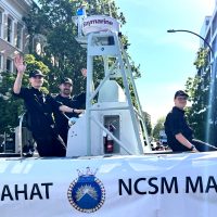 HMCS Malahat on parade: (L-R): Sailor 3rd Class (S3) Cooper Vasey, S3 Malcolm Rorvik, and S3 Callum Leblanc of HMCS Malahat wave to the crowds from aboard one of Malahat’s Rigid Hull Inflatable Boats during the 124th Thrifty Foods Victoria Day Parade in downtown Victoria, May 20. Photo: Lt(N) Donald Den.