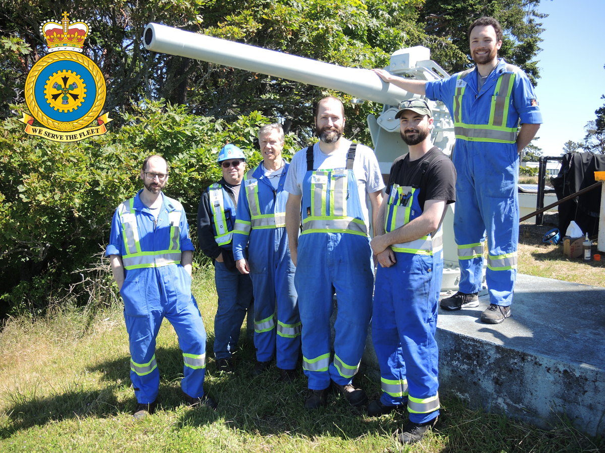 Les membres du Centre de travail sur les armes de surface de l’IMF Cape Breton, atelier 162A, se rassemblent pour une photo de groupe devant le canon de 12 livres à tir rapide situé à la batterie navale de Black Rock, dans l’arsenal CSM. Photo : Peter Mallett/Lookout Newspaper.
